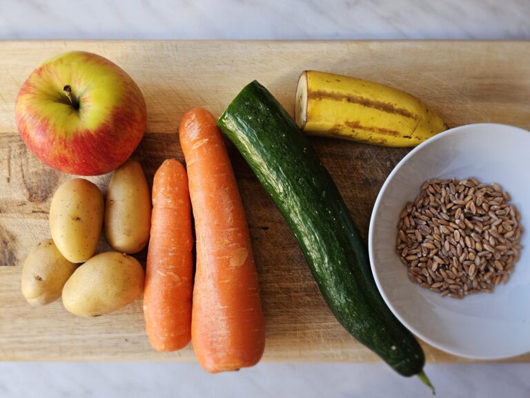 Holzbrett mit Gemüse. Obst und einer Schale Dinkel